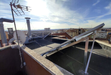 vista posterior de la instalación de 5 paneles en la cubierta plana del edificio de vecinos